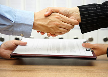 Business partner shaking hand and exhanging contract